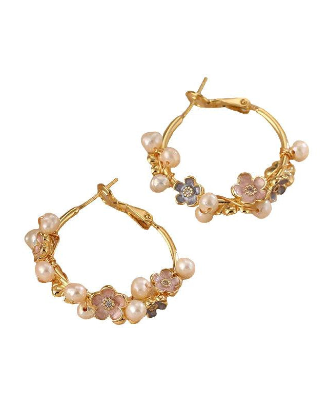 Gold hoop earrings with floral and pearl details on a white background
