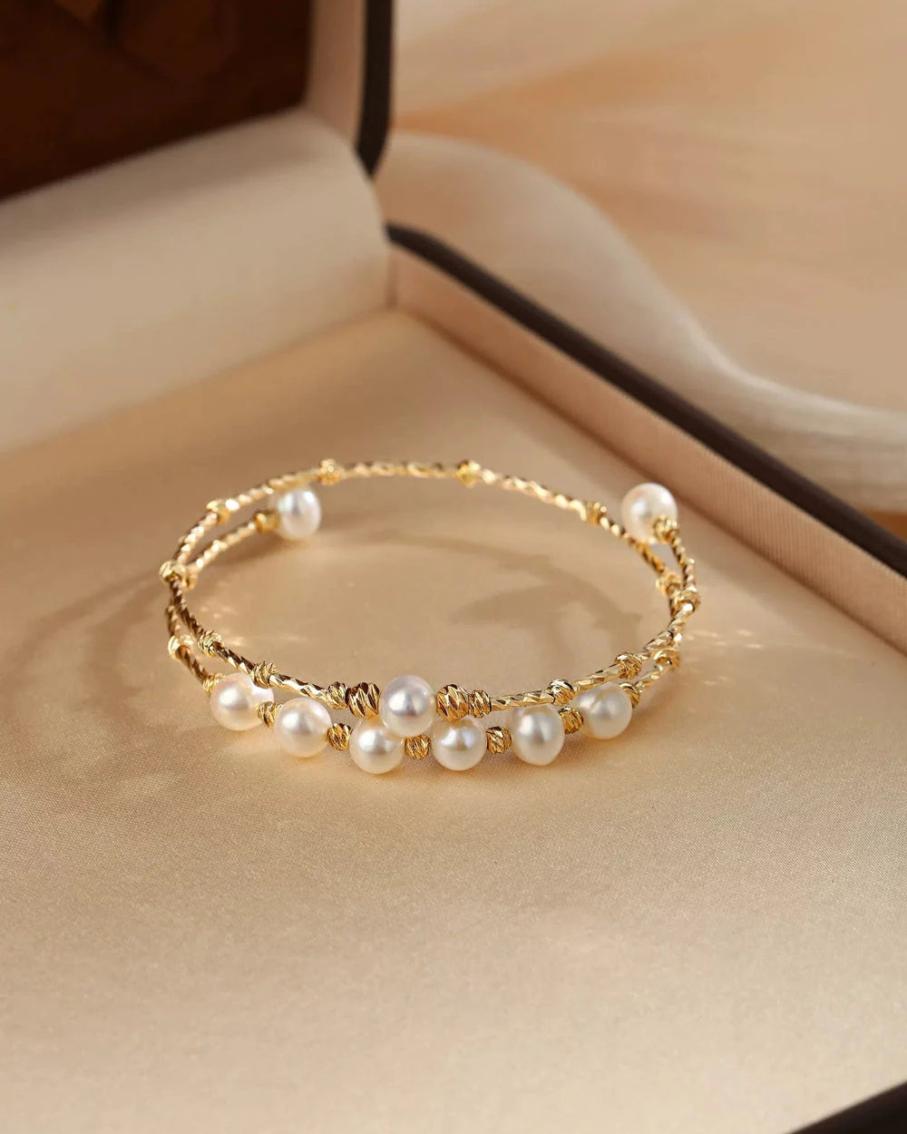 Gold bracelet with pearls on a beige surface