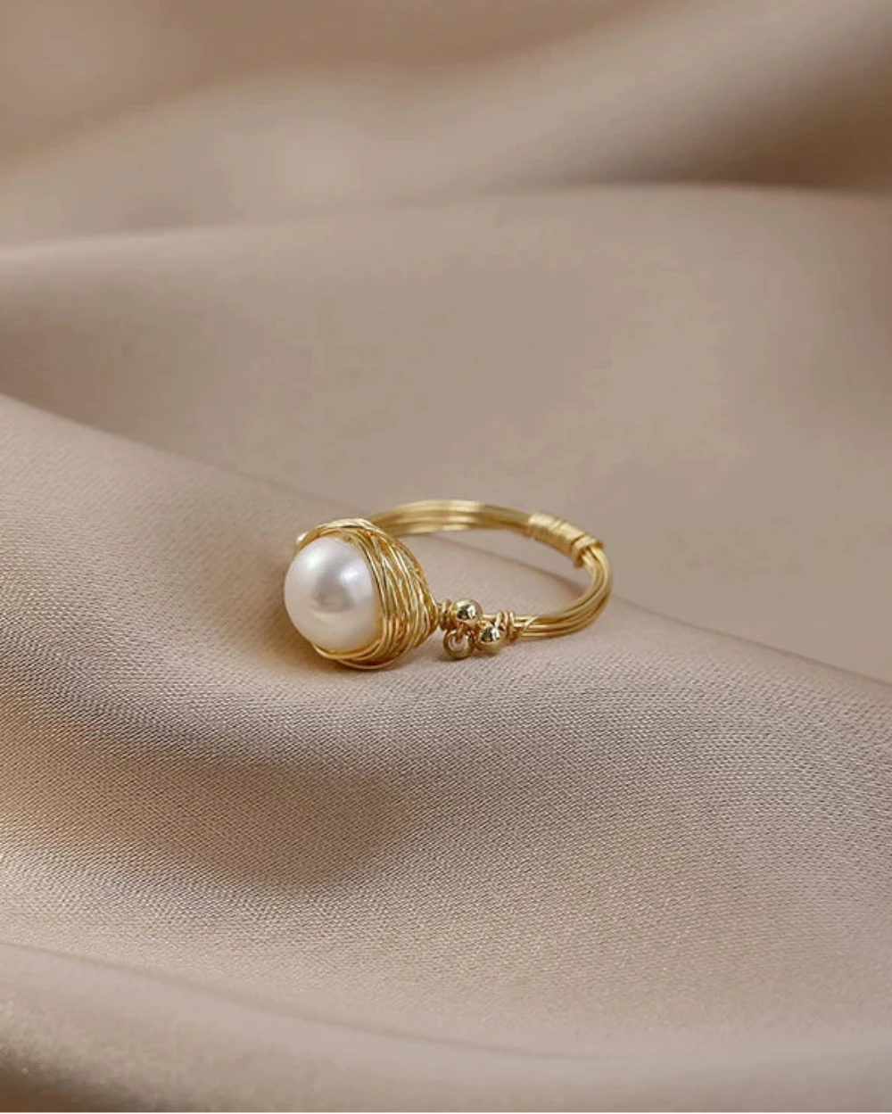 Gold ring with a pearl on a beige fabric background