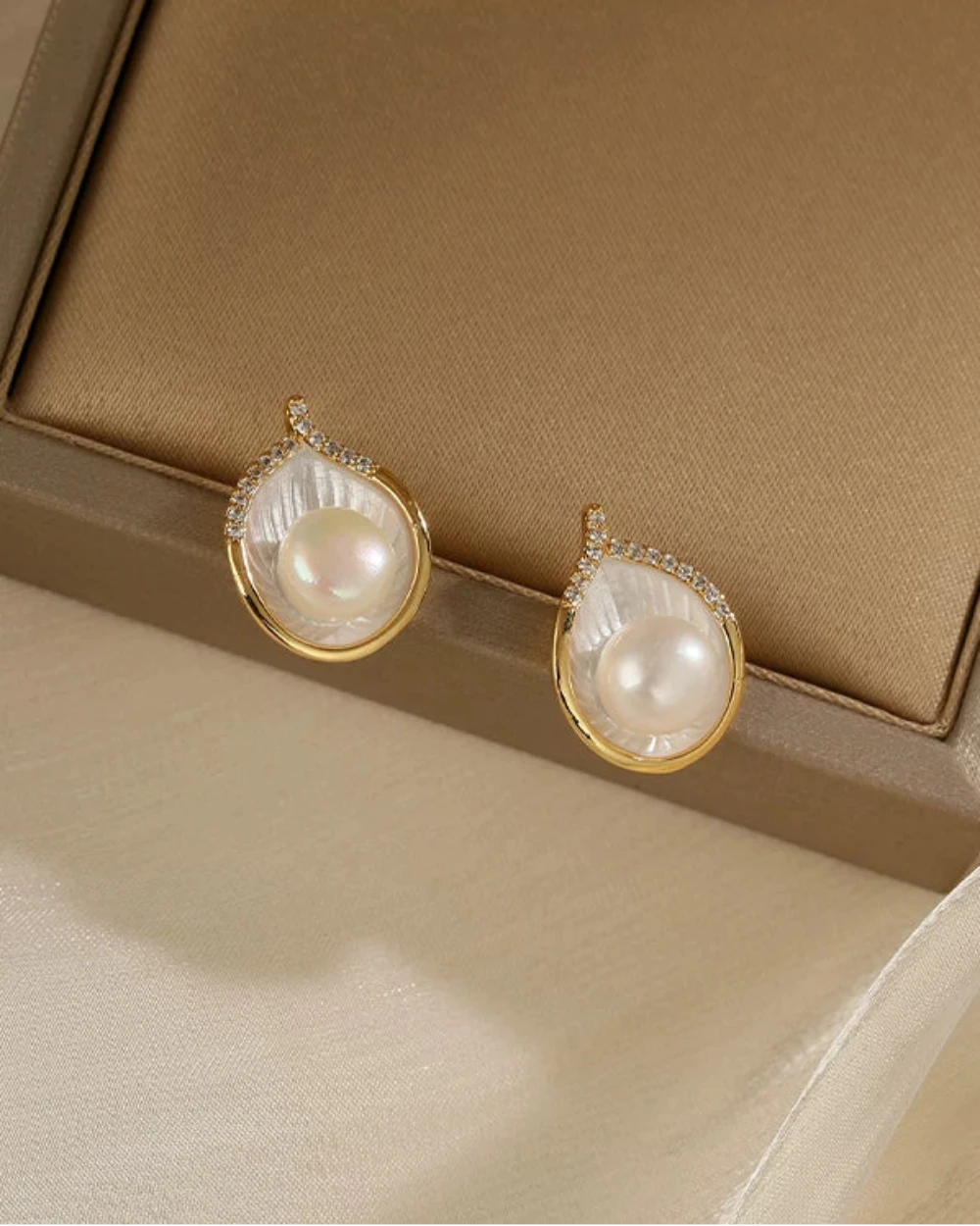 Pearl earrings with gold accents on a beige fabric background