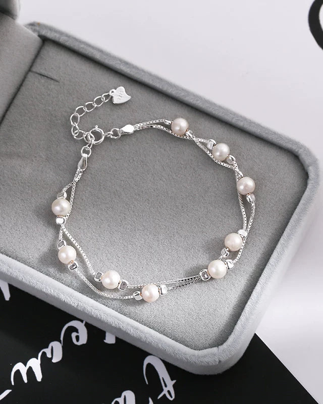 Pearl bracelet on a gray jewelry box with a white background