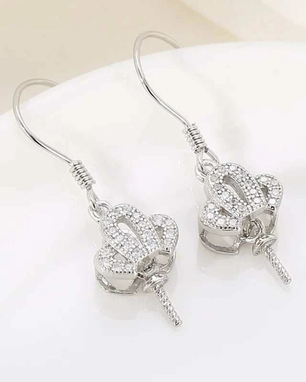 Pair of silver earrings with intricate designs on a white surface