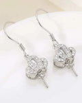 Pair of silver earrings with intricate designs on a white surface