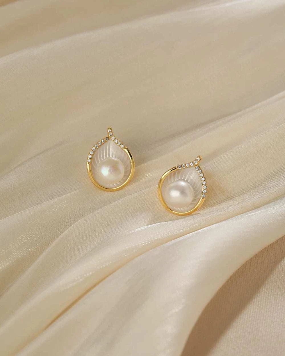 Pearl earrings with gold accents on a beige fabric background