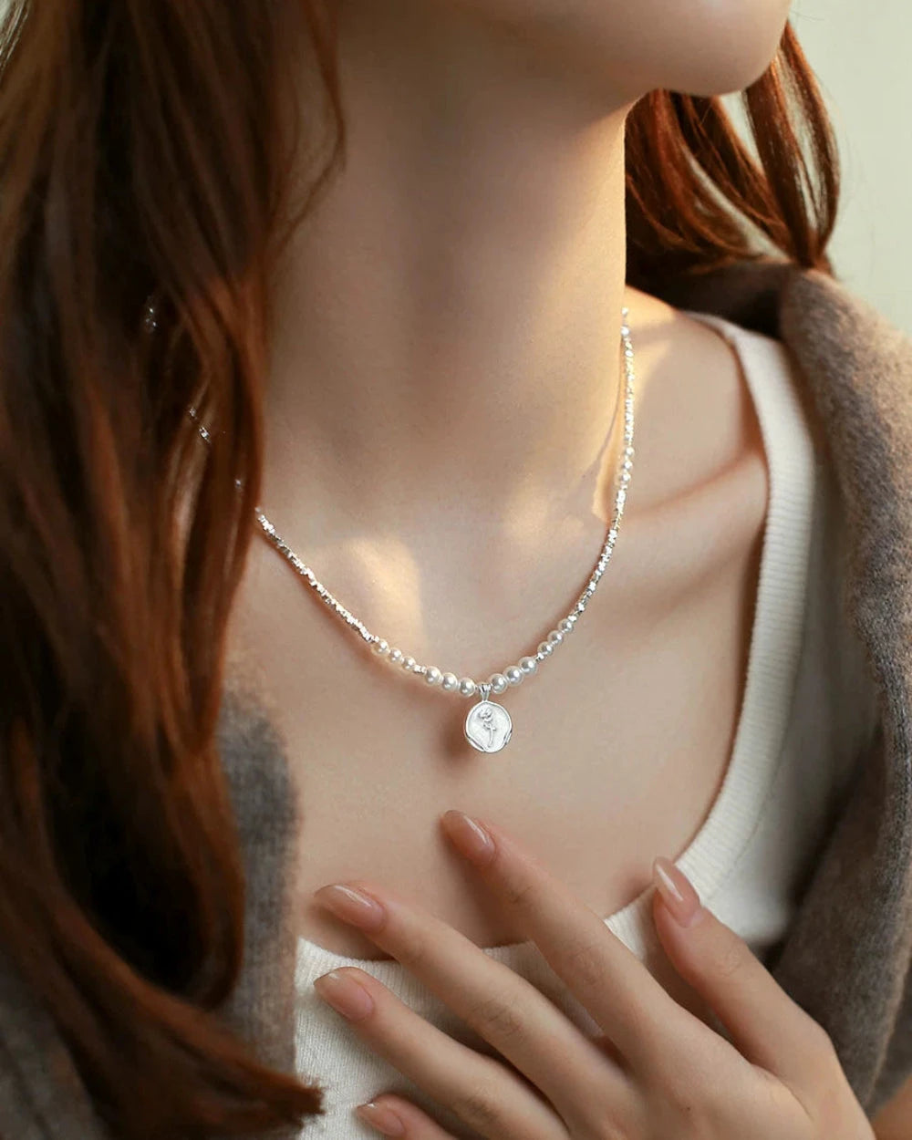 Necklace with a pendant on a mannequin wearing a sweater and cardigan.