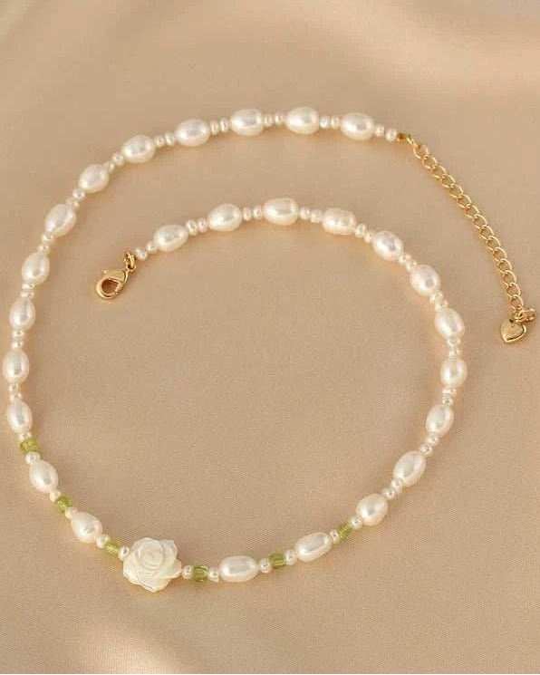 Pearl necklace with a rose charm on a beige background
