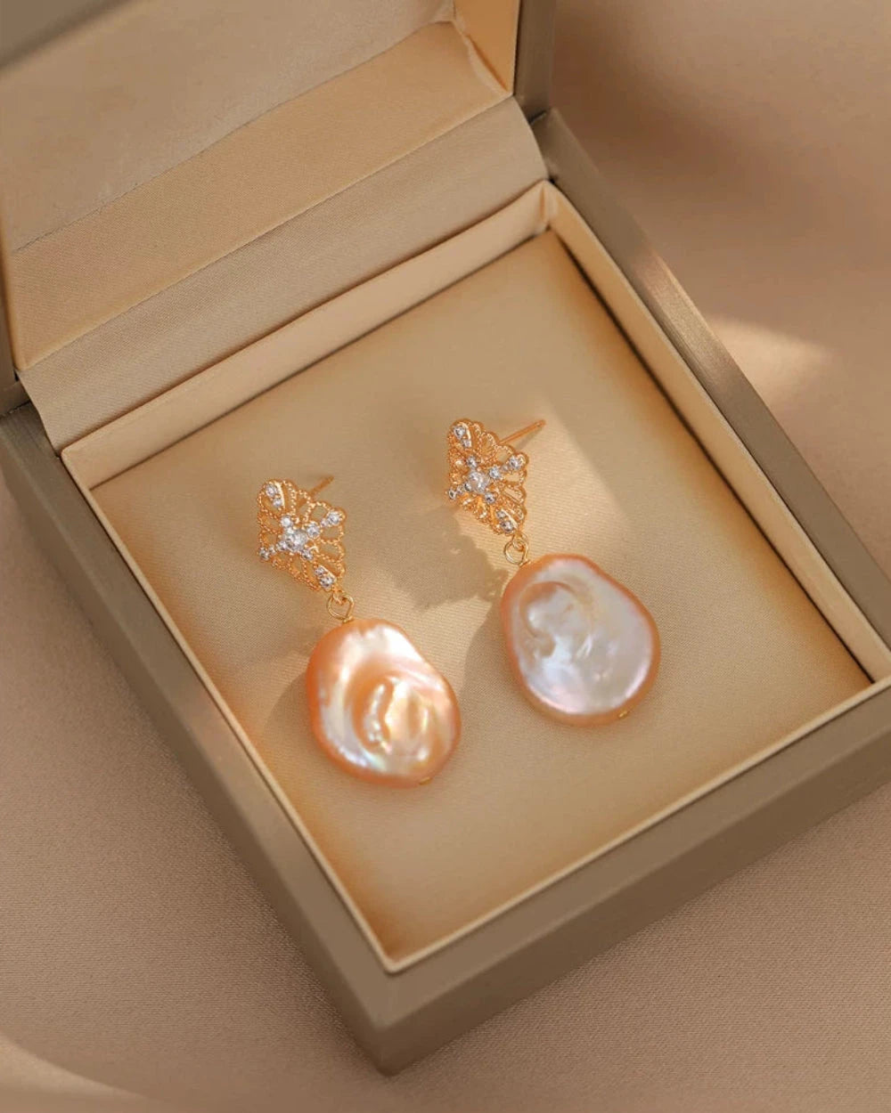 Pair of pearl earrings in a beige jewelry box