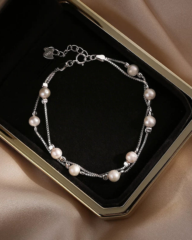 Pearl bracelet on a black display card with a beige fabric background