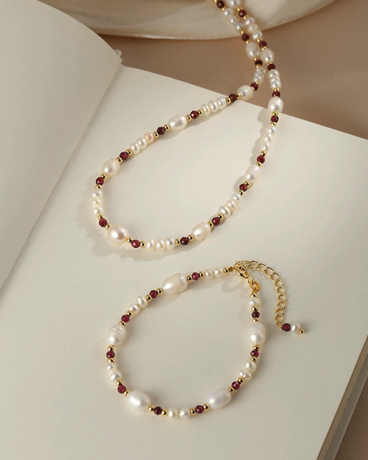 Pearl and red bead necklace on a white surface