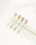 Four metallic safety pins in silver, gold, and rose gold on a white background