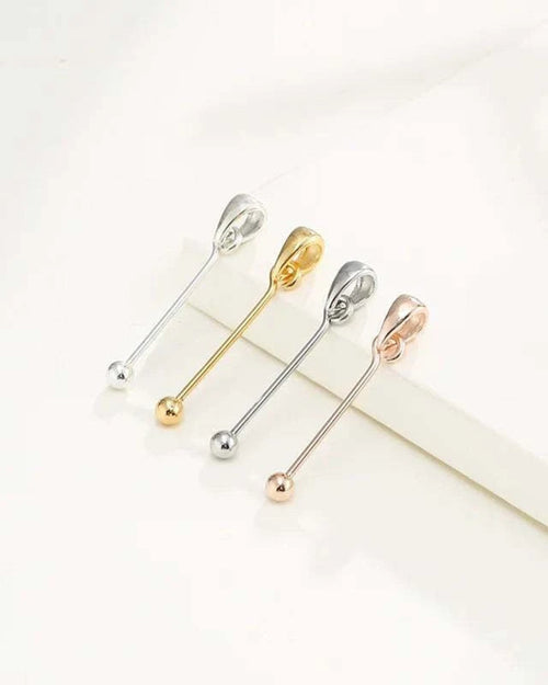 Four metallic safety pins in silver, gold, and rose gold on a white background