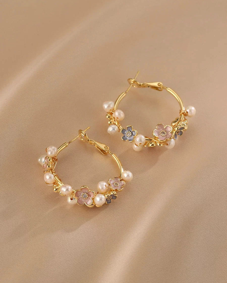Gold hoop earrings with pearl and gemstone accents on a beige background