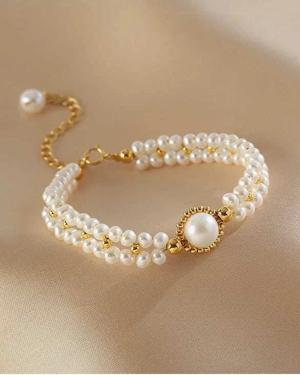 Pearl bracelet with gold accents on a beige fabric background