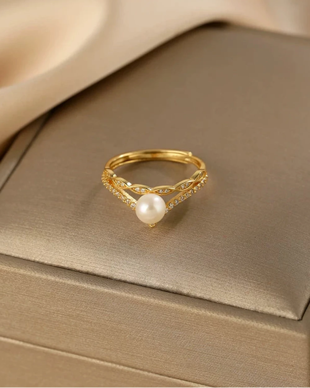 Gold ring with a pearl on a beige satin surface