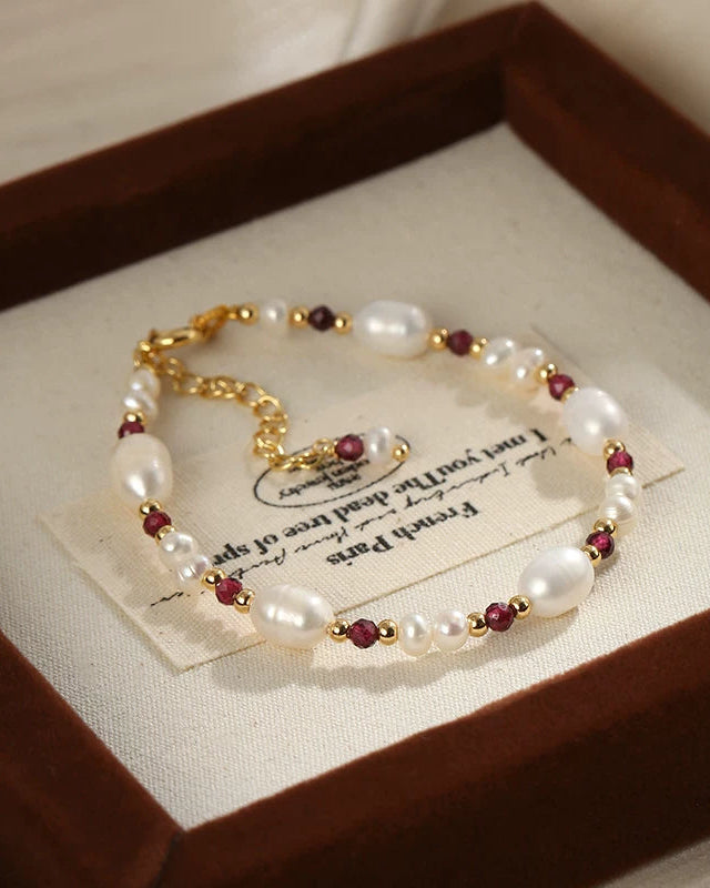 Pearl bracelet with red beads on a card inside a wooden box