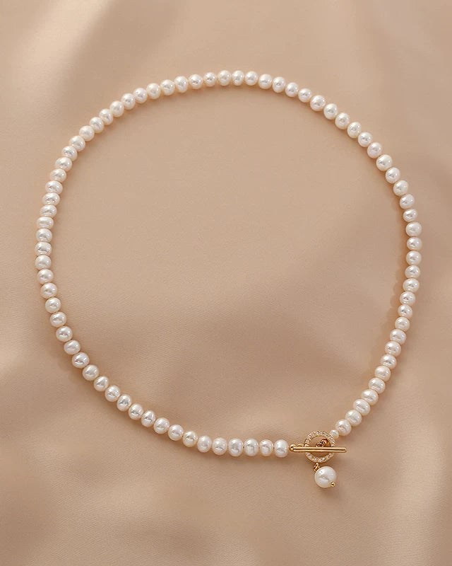 Pearl necklace with a gold clasp on a beige fabric background