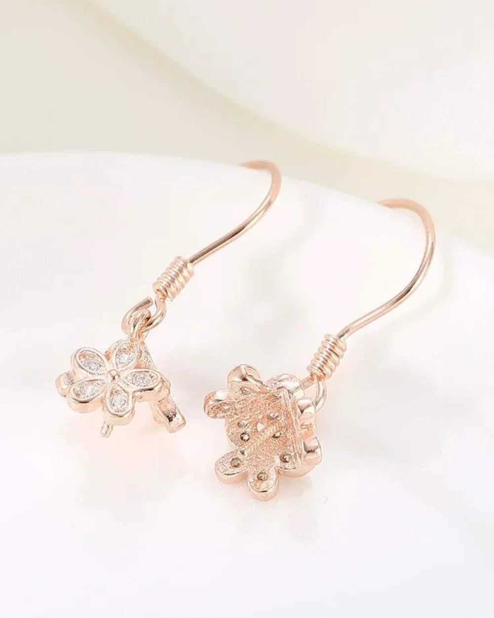 Rose gold earrings with floral designs on a light background