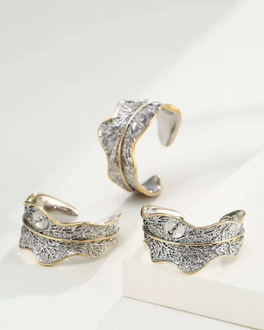 Three silver and gold earrings on a white surface