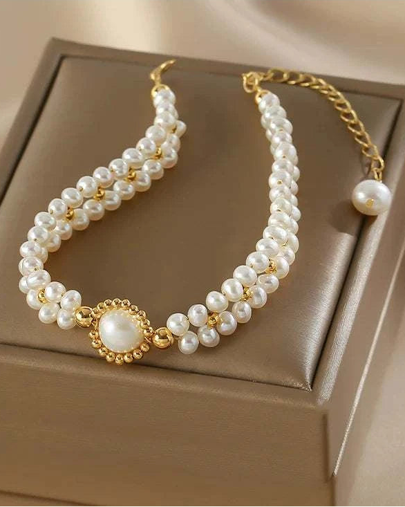Pearl necklace with gold accents on a beige box