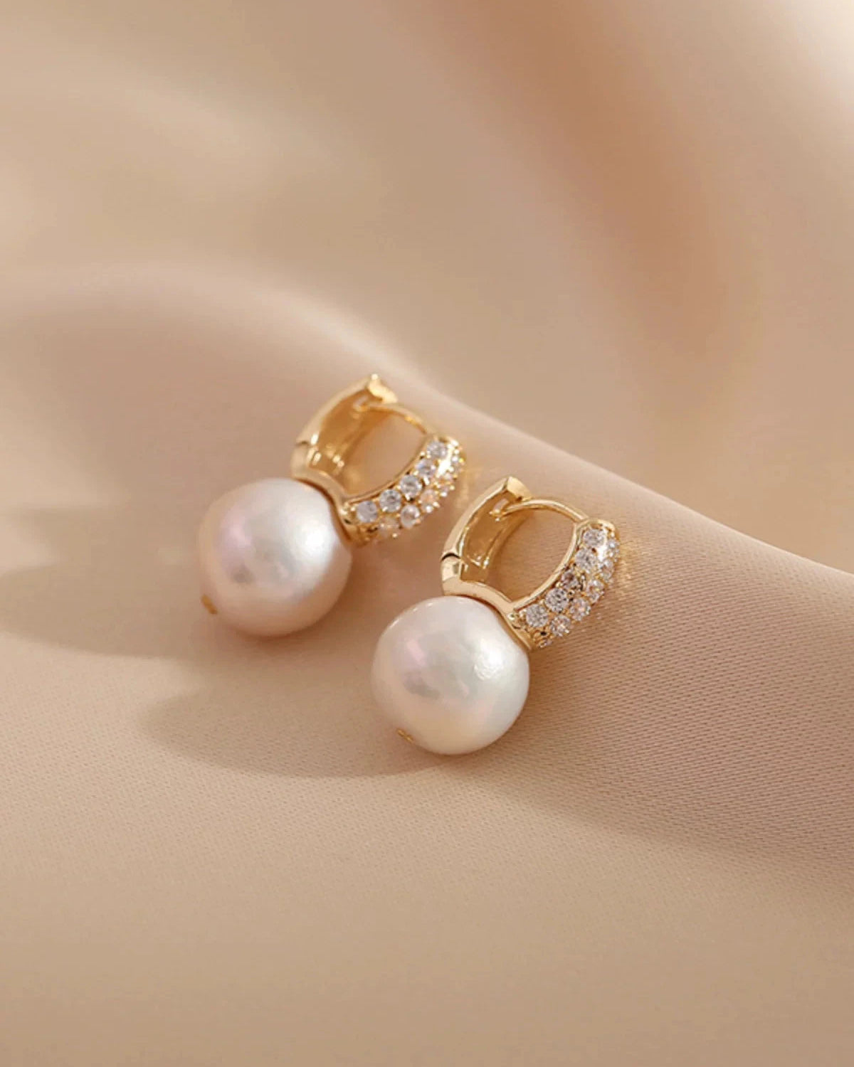 Pearl earrings with gold accents on a beige surface
