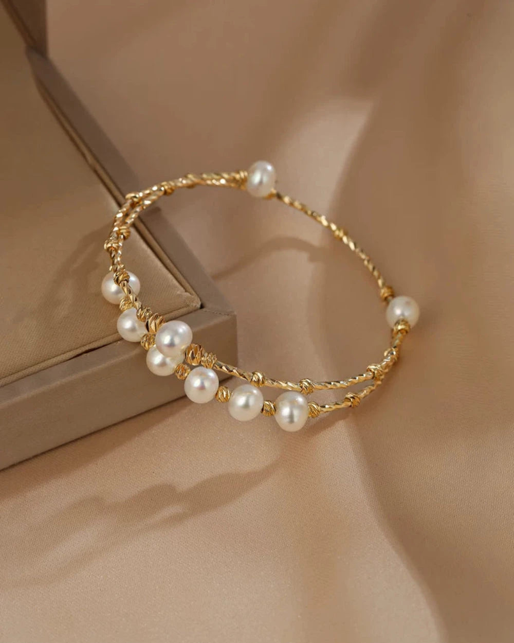 Gold bracelet with pearls on a beige background