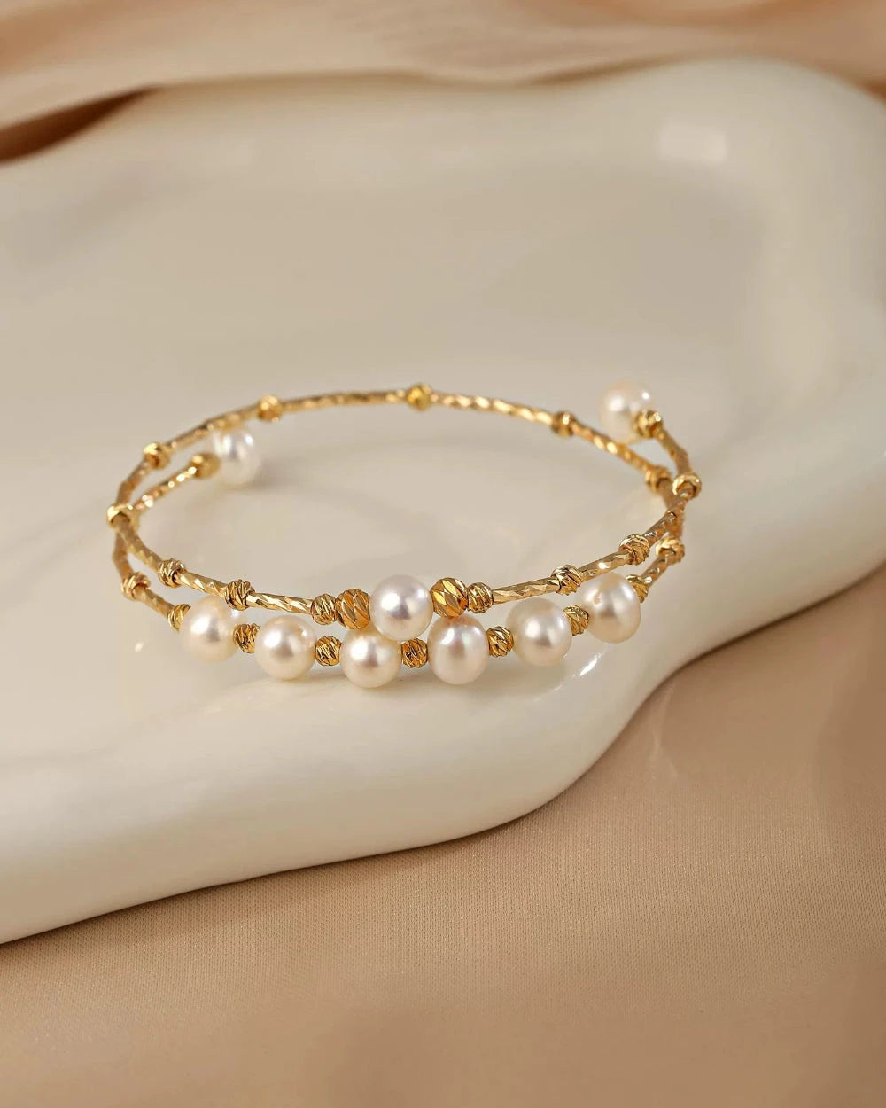Gold bracelet with pearls on a beige surface