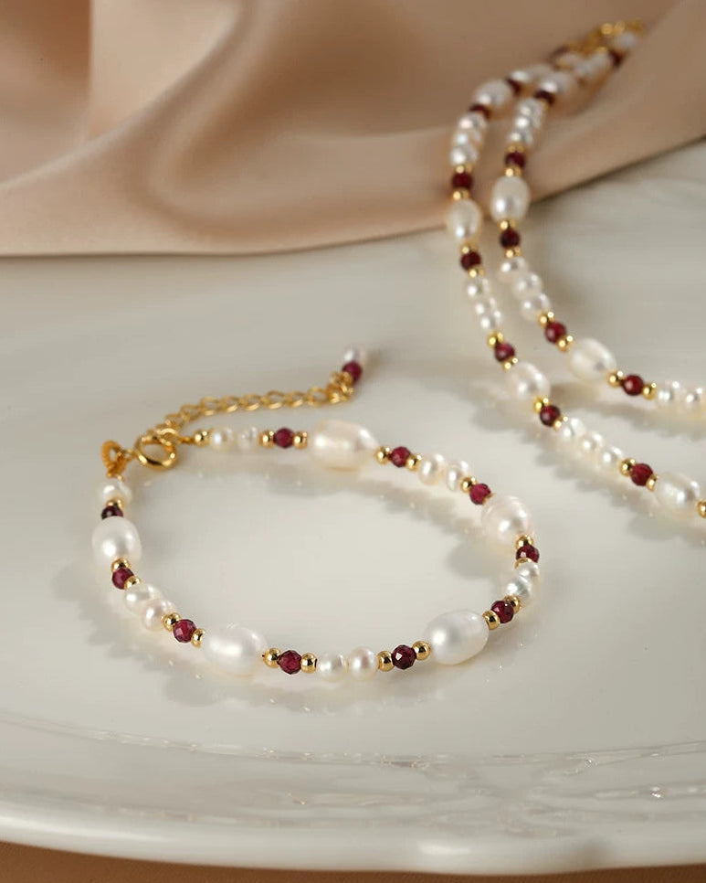 Pearl and red bead bracelet on a white plate with a beige background