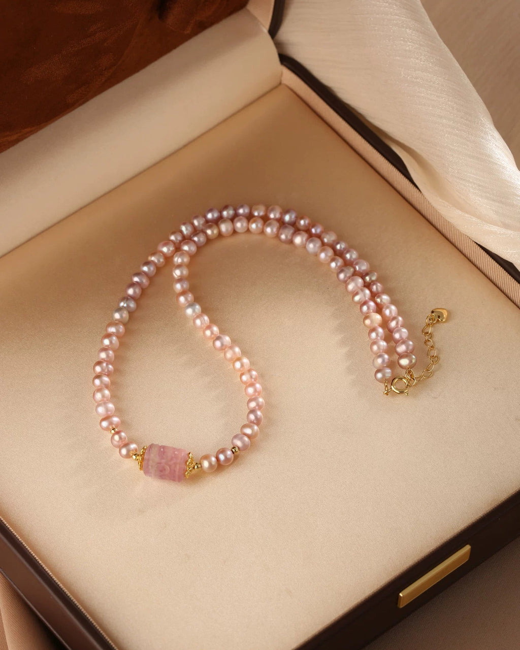 Pearl necklace with gold clasp on a beige jewelry box