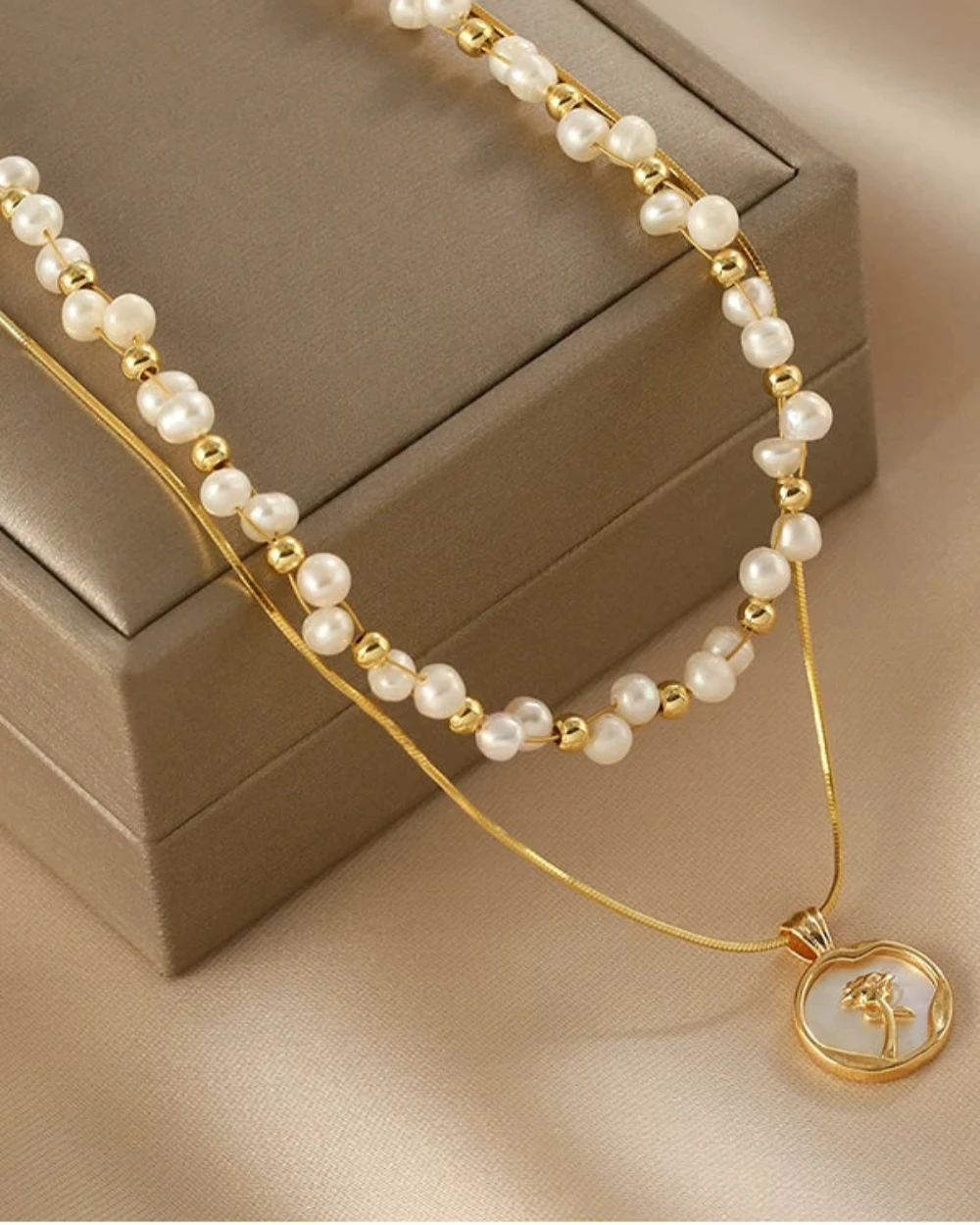 Pearl necklace with gold accents and a pendant on a beige fabric background