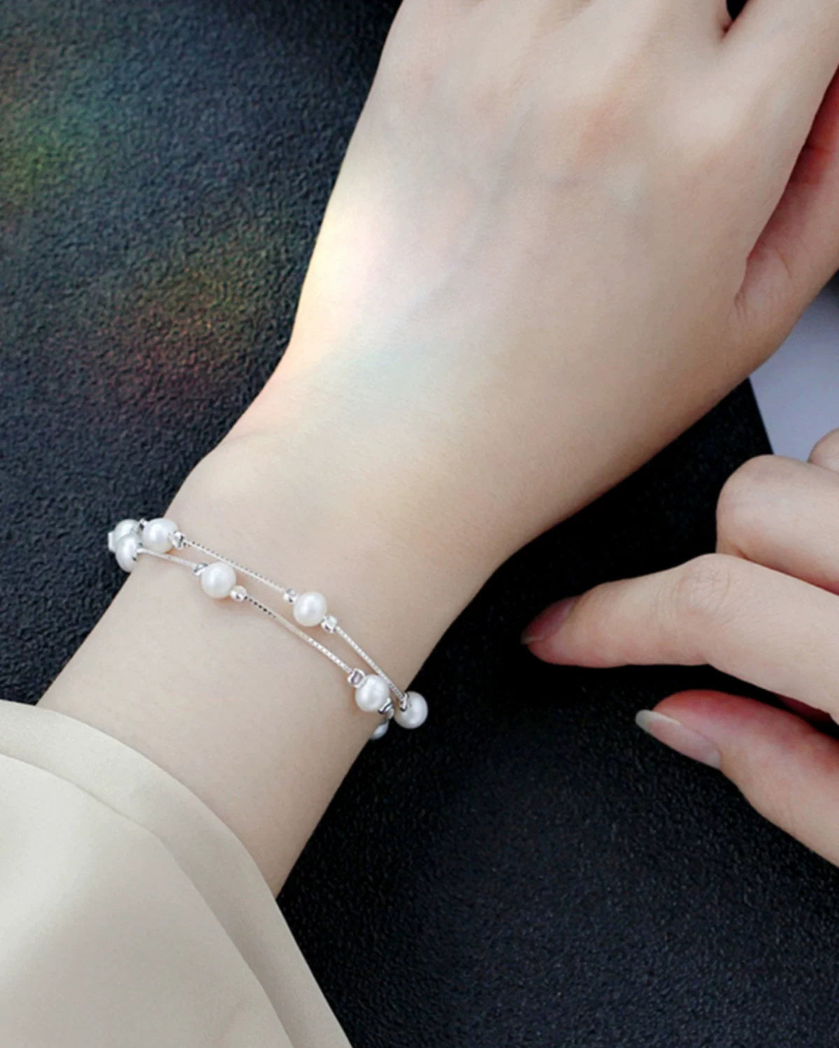 Pearl bracelet on a wrist against a dark background