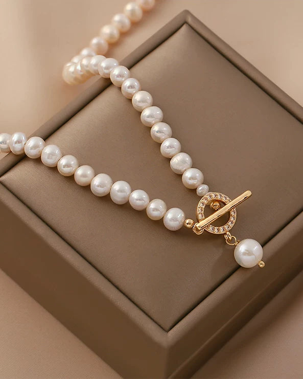Pearl necklace with a gold clasp on a brown jewelry box