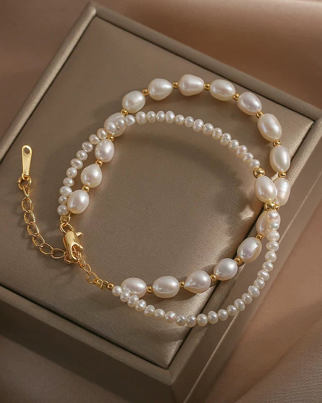 Pearl bracelet with gold chain on a beige jewelry box