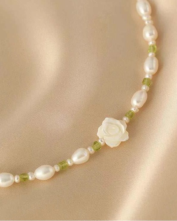 Pearl necklace with a white flower pendant on a beige fabric background