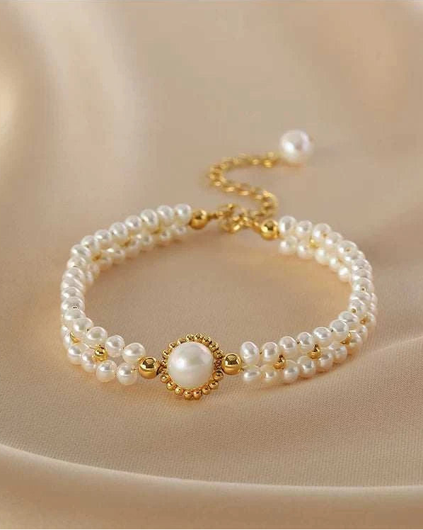 Pearl bracelet with gold accents on a beige fabric background