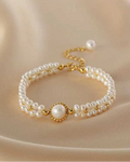 Pearl bracelet with gold accents on a beige fabric background