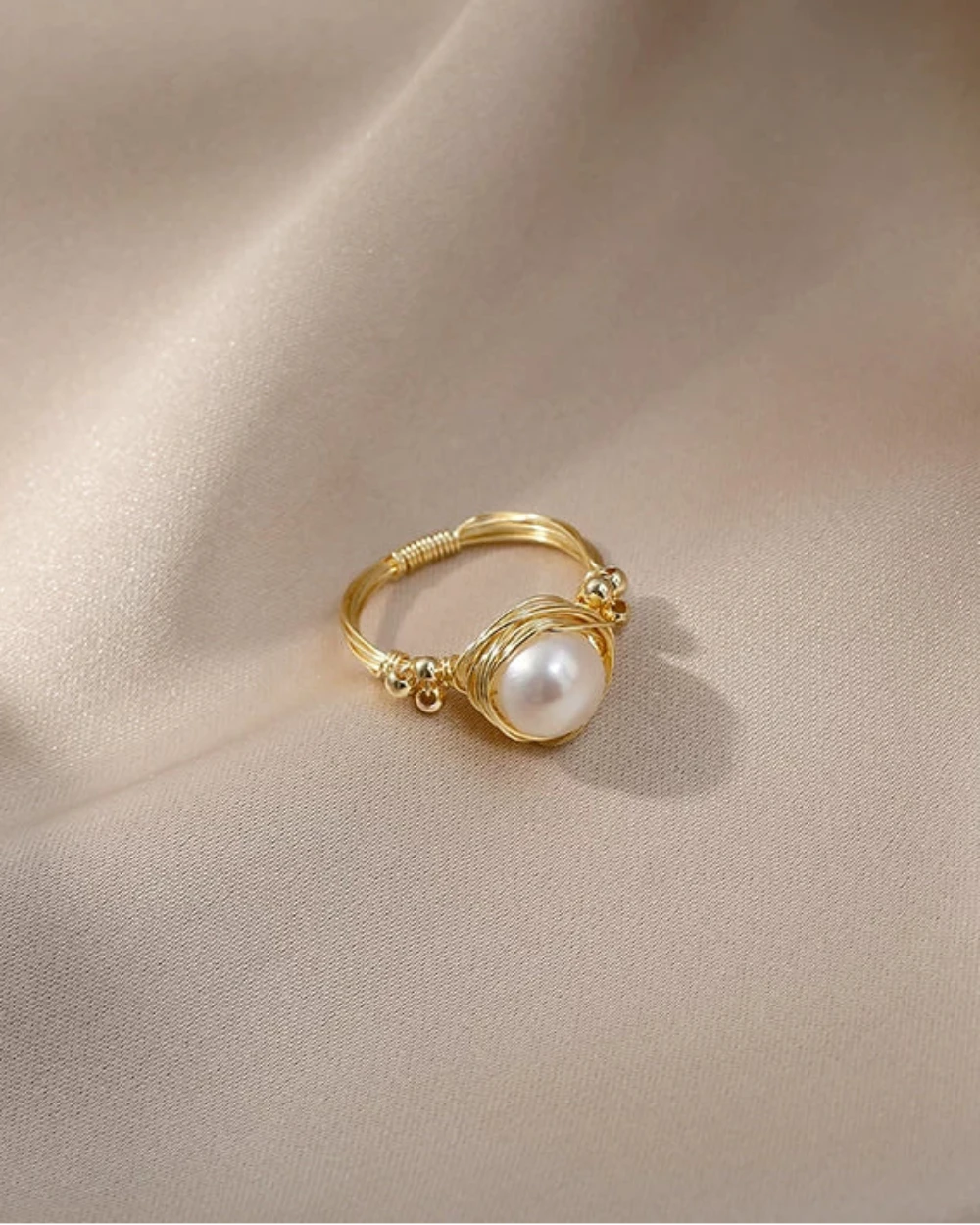 Gold ring with a pearl on a beige fabric background
