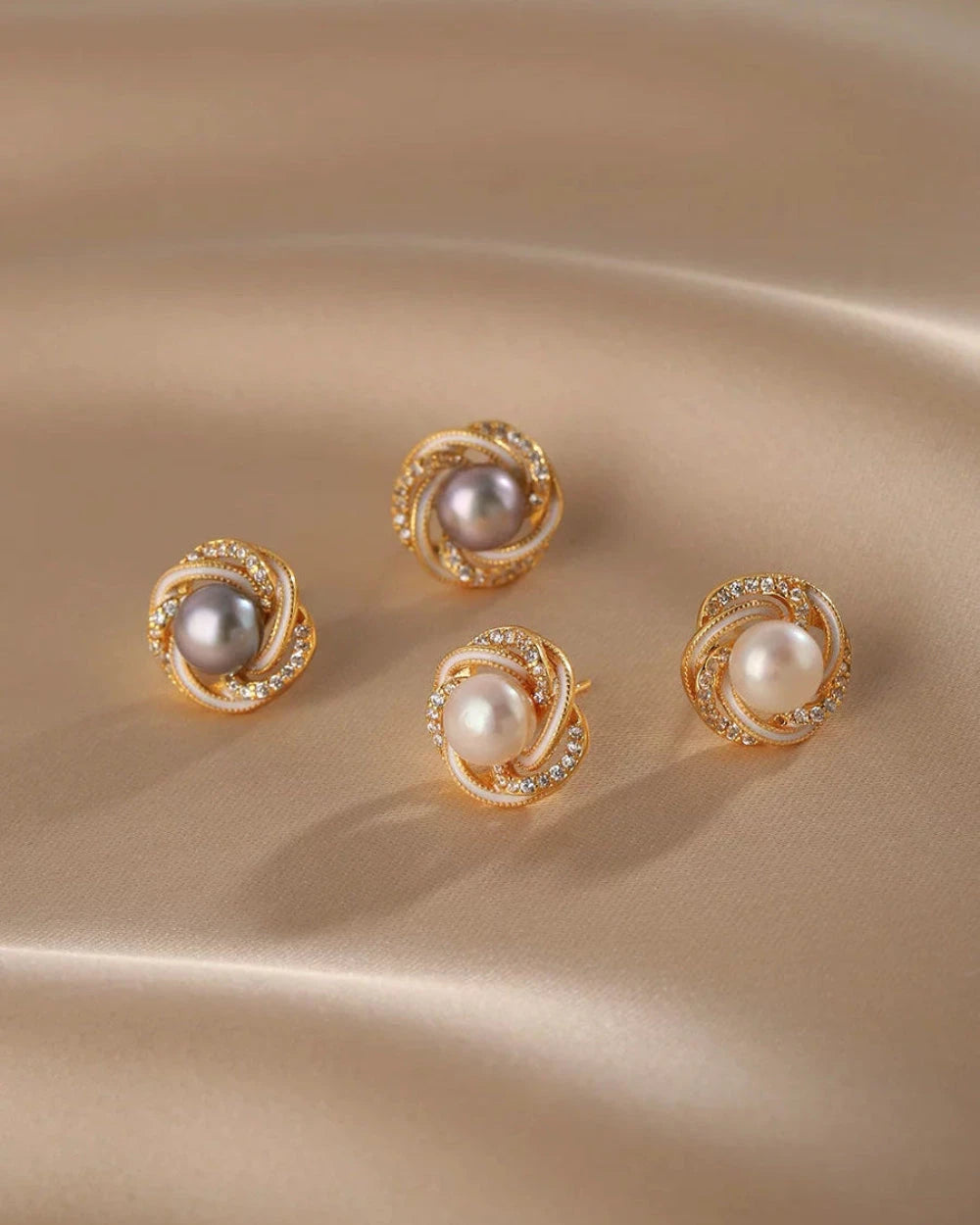 Set of gold earrings with pearls on a beige fabric background