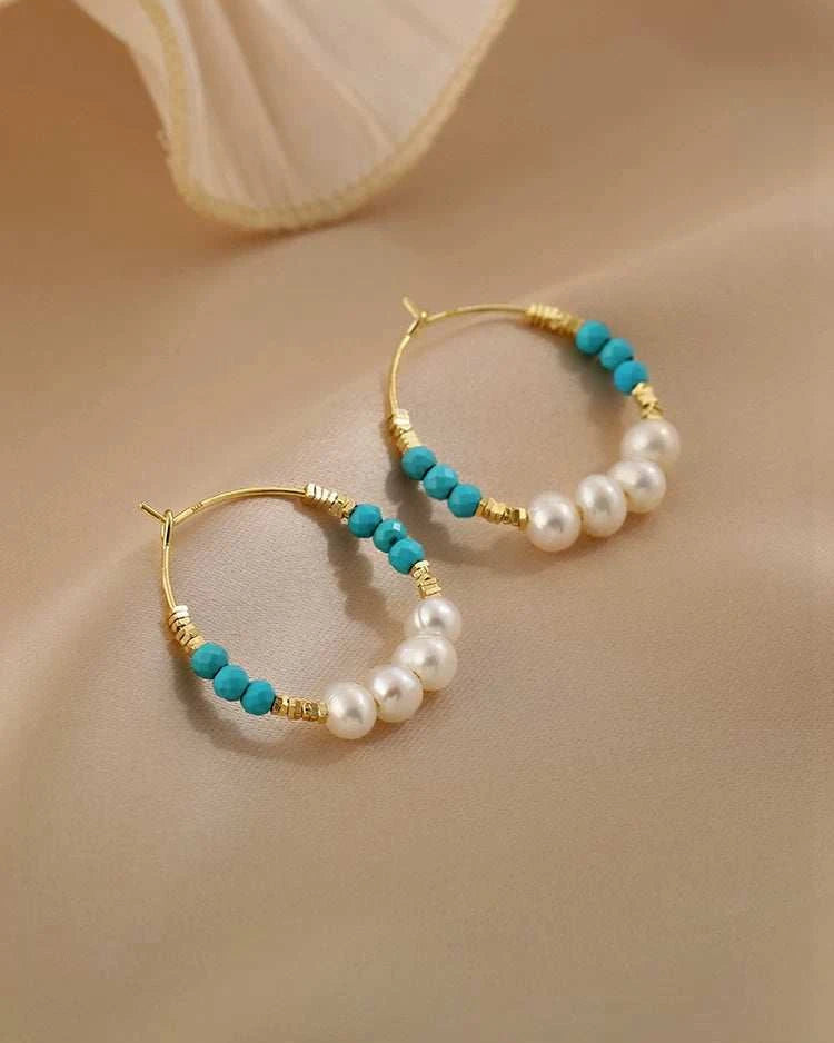 Hoop earrings with turquoise beads and pearls on a beige background