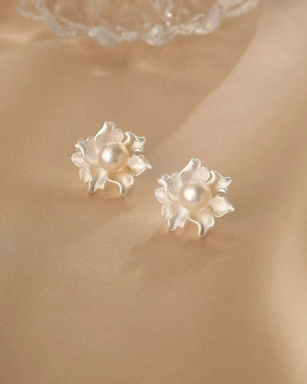 Pair of floral earrings with pearls on a beige background