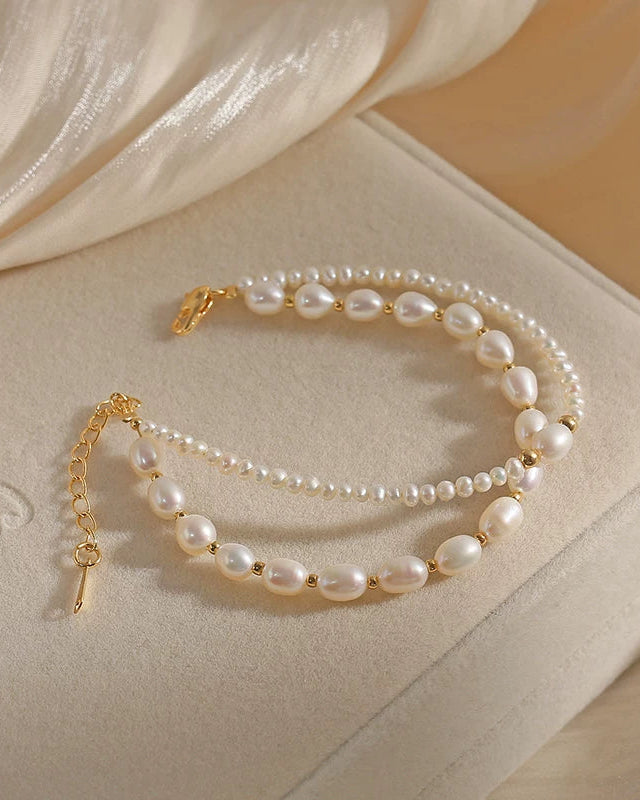 Pearl bracelet with gold accents on a beige surface