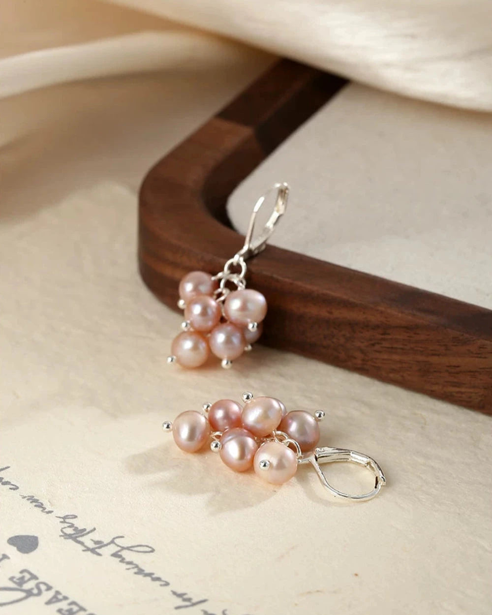 Pair of pearl earrings on a wooden stand with a soft background