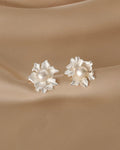 Pair of silver earrings with pearl centers on a beige fabric background
