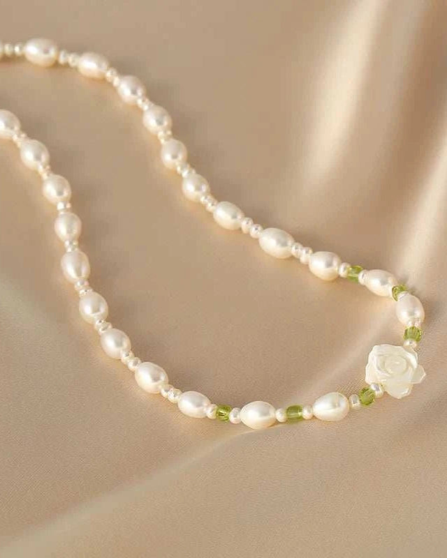 Pearl necklace with a white flower pendant on a beige fabric background