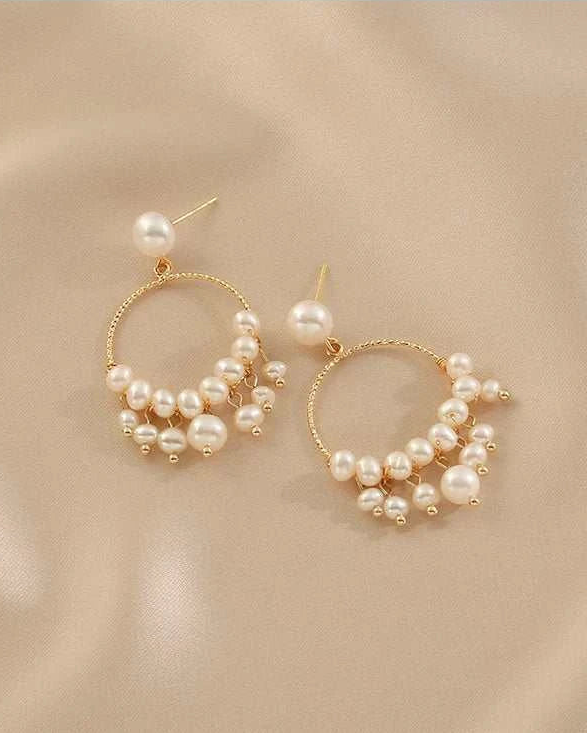 Gold hoop earrings with pearls on a beige background