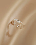 Silver open ring on a beige fabric background