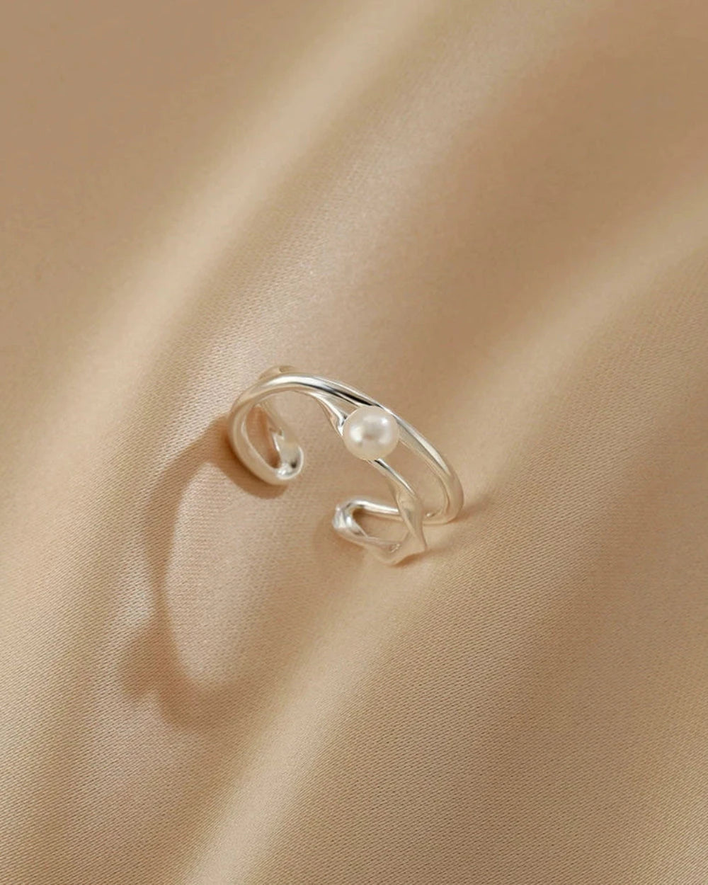 Silver open ring on a beige fabric background
