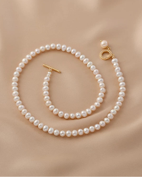 Pearl necklace with gold clasp on a beige fabric background