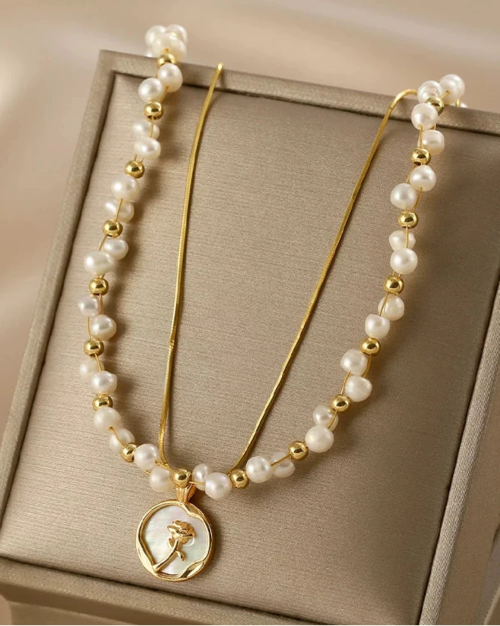 Pearl necklace with gold accents on a beige jewelry box