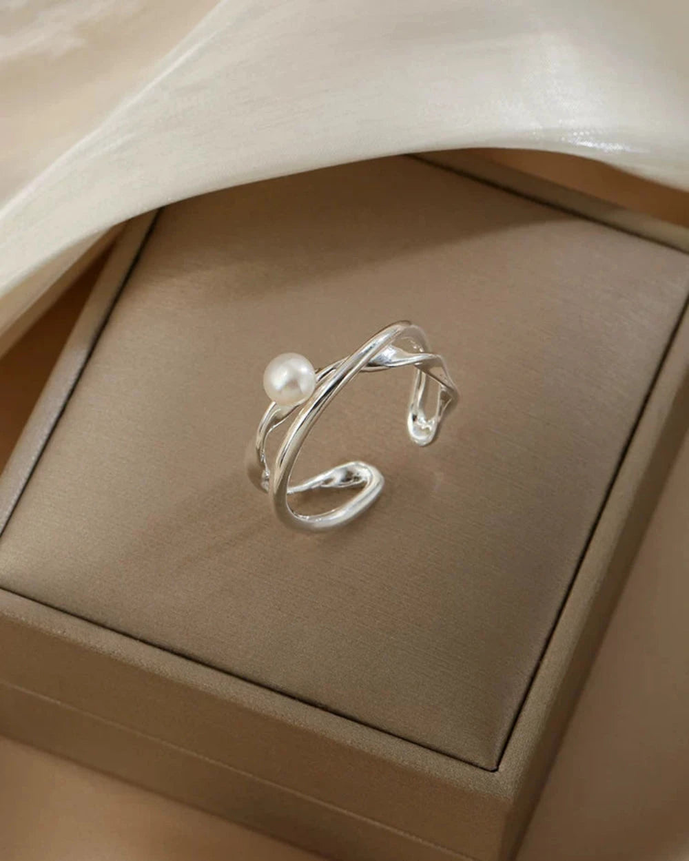 Silver ring with a pearl on a beige jewelry box