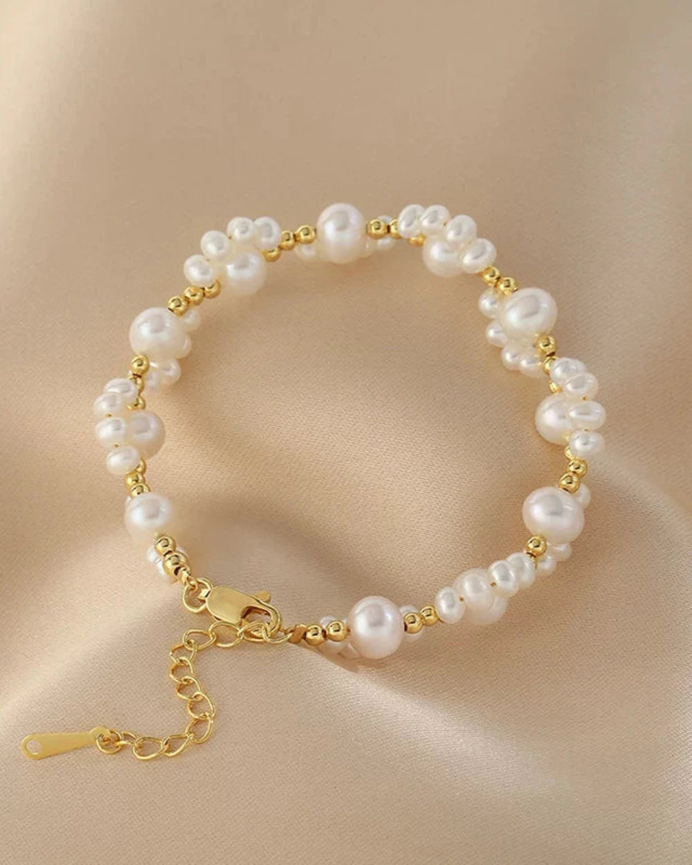 Pearl bracelet with gold accents on a beige fabric background